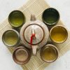 ceramics-tea-cups-surrounded-with-teapot-placemat-concrete-backdrop